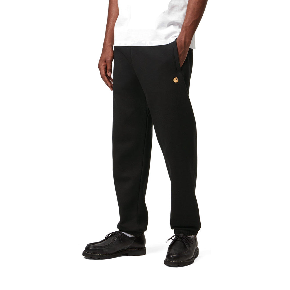 Pantaloni della tuta Carhartt WIP Chase Sweat Pant Black / Gold – indossati vista di tre quarti