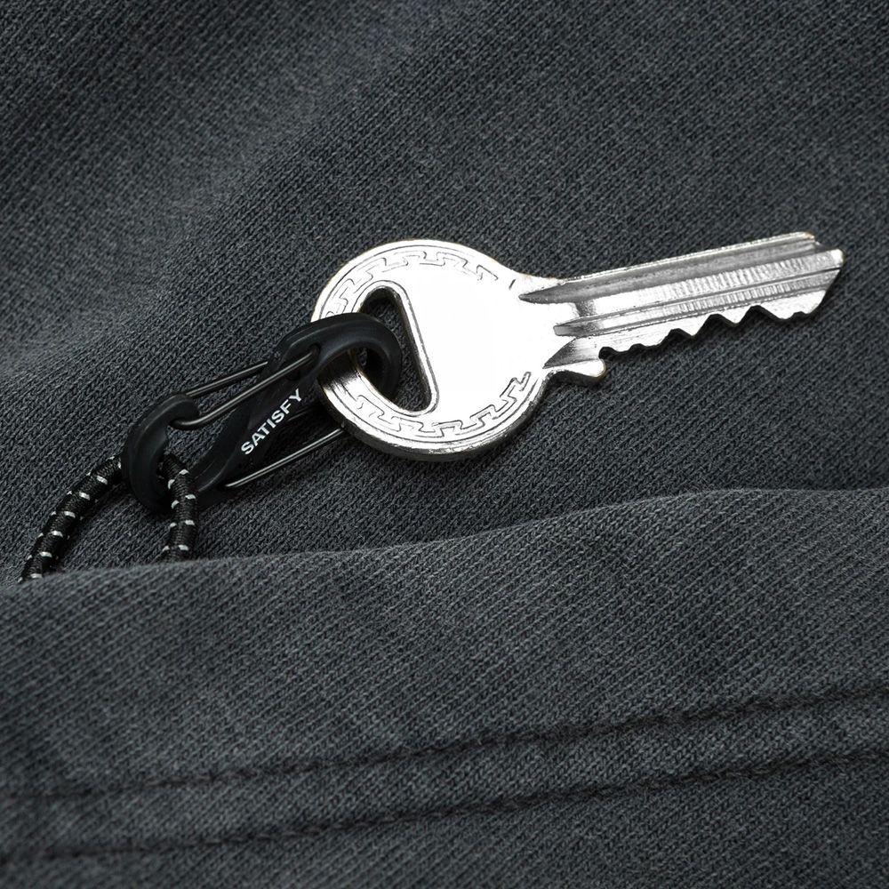 Felpa Satisfy SoftCell Hoodie Aged Black – dettaglio del moschettone S-Carabiner nella tasca